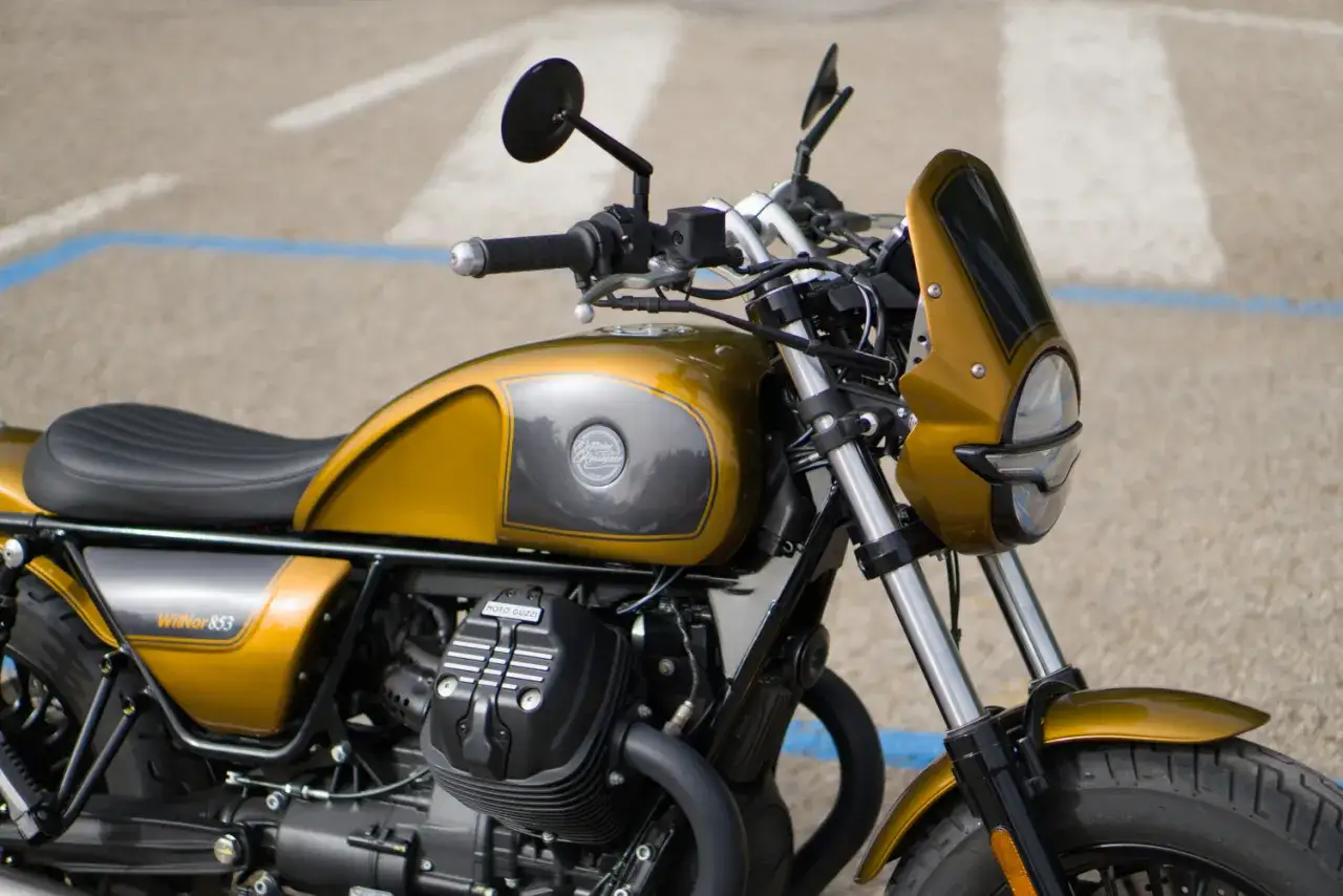 Złoty motocykl Moto Guzzi V9 z czarnym siedzeniem i niewielką owiewką.