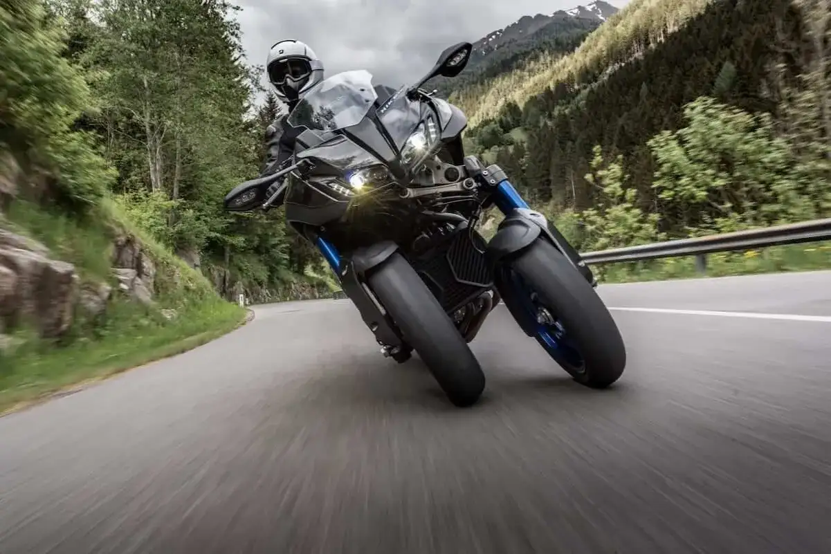 Motocyklista na czarnym Yamaha Niken pokonuje zakręt górskiej drogi.