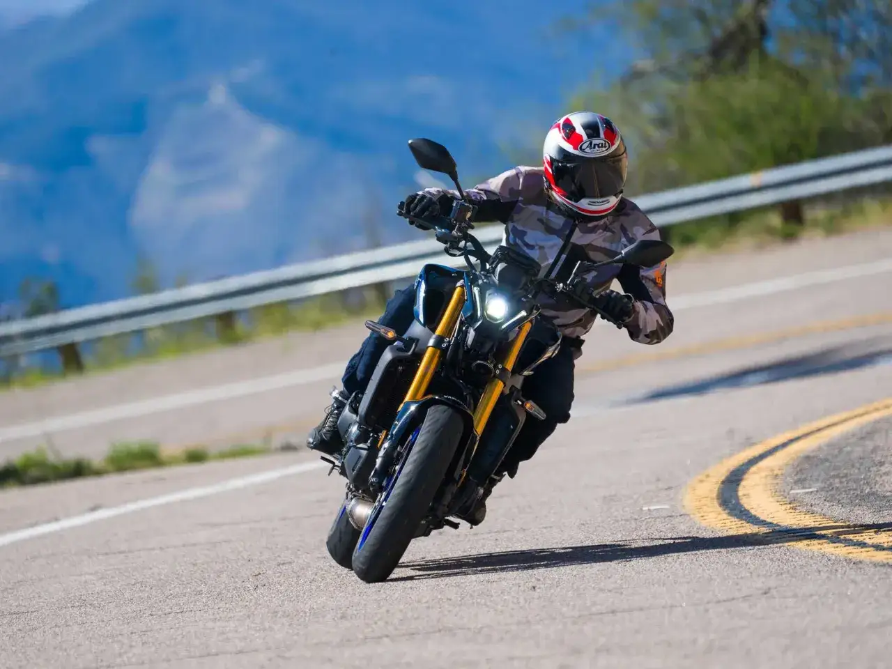 Motocyklista na Yamaha MT09 pochyla się na zakręcie górskiej drogi, ciesząc się jazdą.