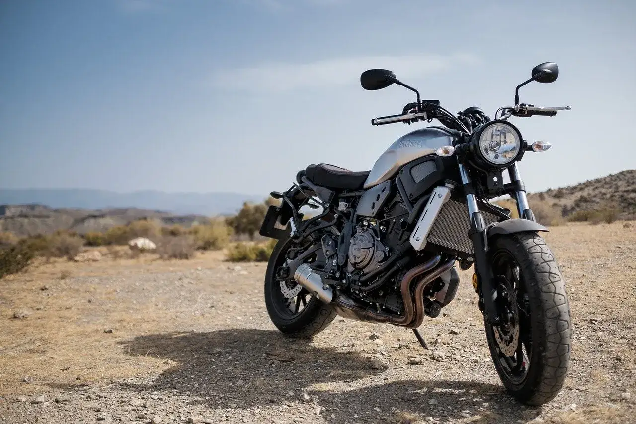 Srebrny motocykl typu naked bike na pustynnym tle.