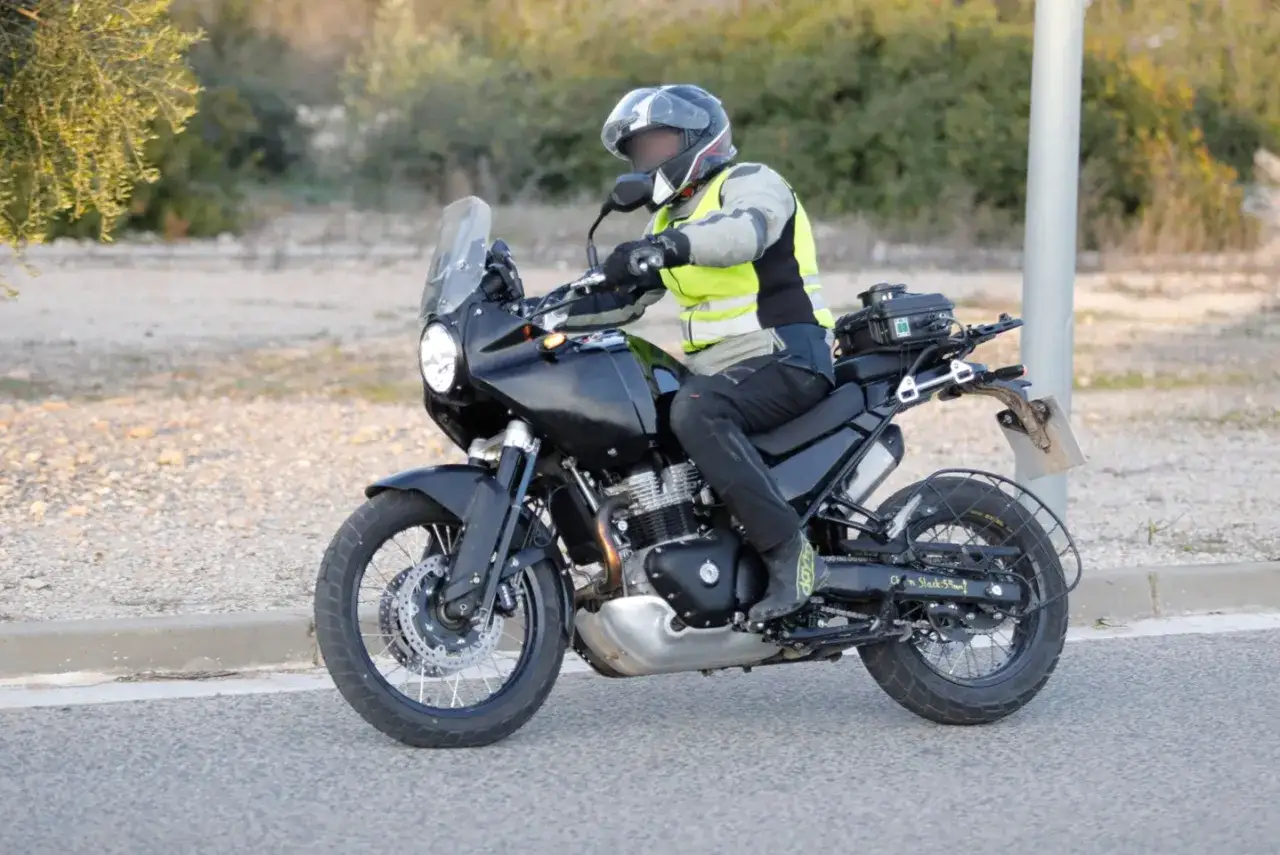 Motocyklista w kamizelce odblaskowej na czarnym Royal Enfield Himalayan 650, gotowy na przygodę.