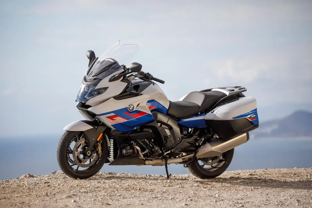 Biało-niebieski motocykl BMW K 1600 na tle morza. Choć piękny, jego wady mogą być znaczące dla niektórych kierowców.