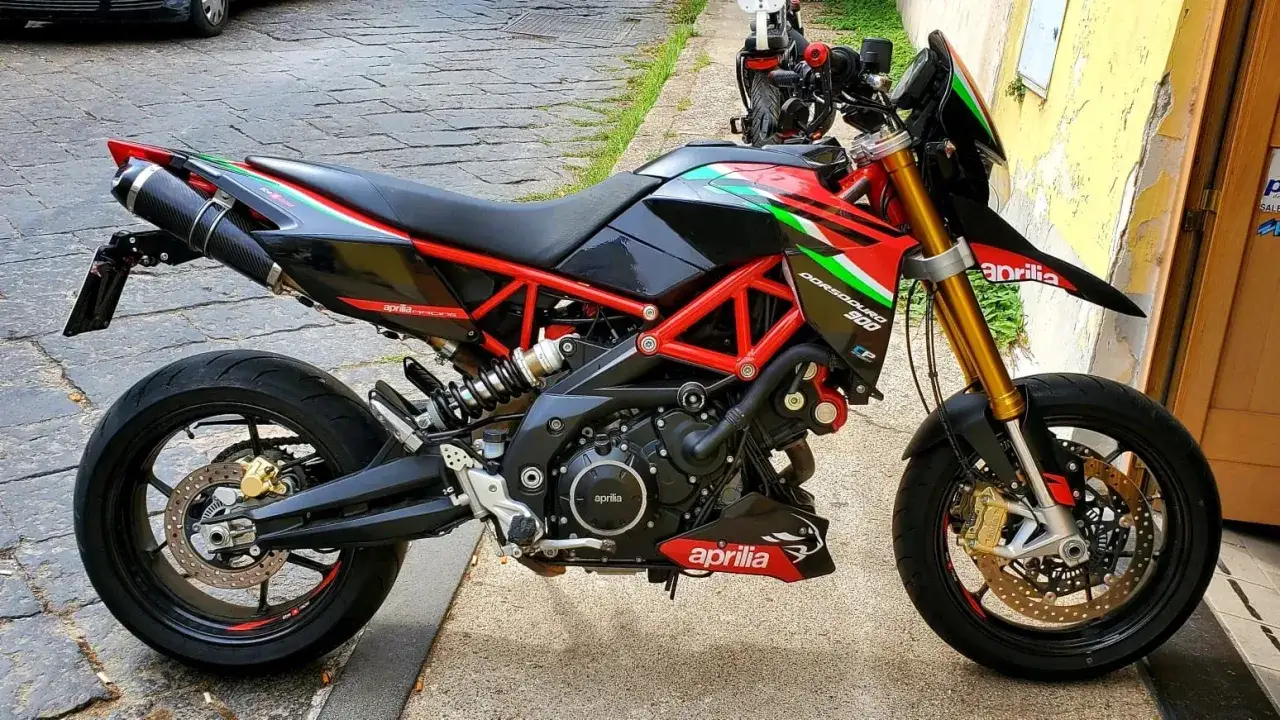 Sportowy motocykl Aprilia Dorsoduro 750 w kolorach włoskiej flagi, z czarnym lakierem i czerwonym stelażem, gotowy do jazdy.
