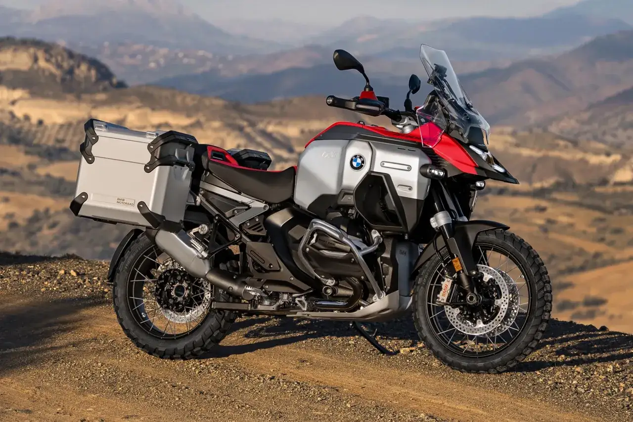 Nowy motocykl BMW R1300GS gotowy na przygodę w górskim krajobrazie.