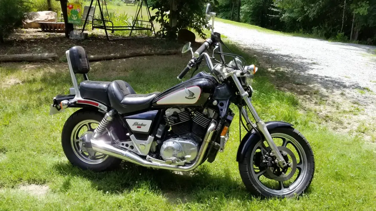 Czarny motocykl Honda Shadow 1100, z chromowanymi elementami i wygodnym siedzeniem, gotowy do jazdy. Dane techniczne tego modelu są imponujące.
