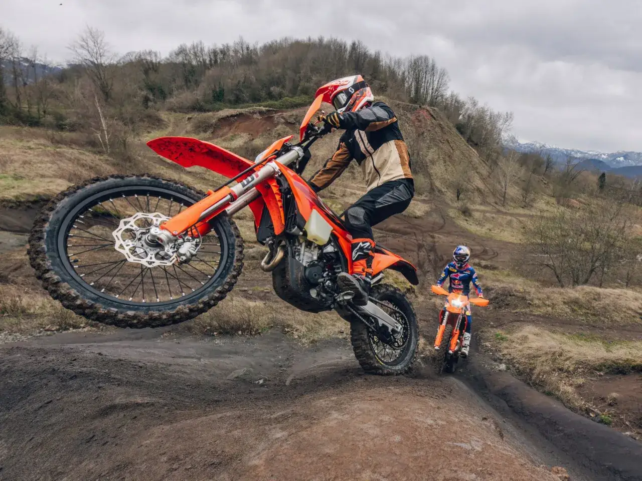 Motocyklista na KTM EXC 450 w powietrzu, drugi motocyklista w tle. Poznaj dane techniczne KTM EXC 450.