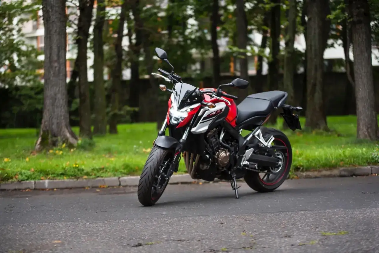 Czerwono-biały motocykl Honda CB650F na tle drzew. Poznaj jego honda cb650f dane techniczne i możliwości.