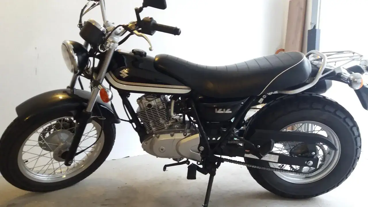 Czarny Suzuki Van Van 125 z chromowanymi detalami i wygodnym siedzeniem, gotowy na miejskie przygody.