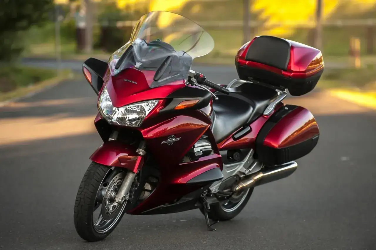 Czerwony motocykl Honda ST 1300, z kuframi i dużą szybą. Choć piękny, ma swoje wady, jak każdy sprzęt.