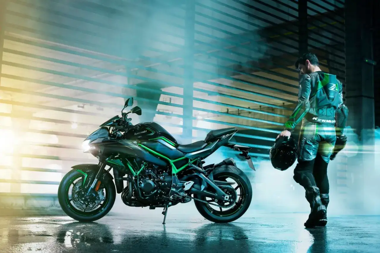 Czarny motocykl Kawasaki Z900 z zielonymi akcentami, obok kierowca w kombinezonie.