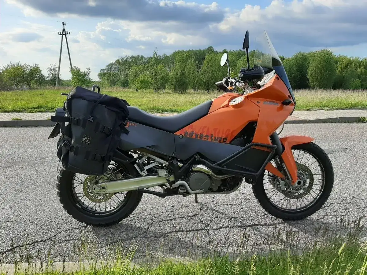 Pomarańczowy KTM 990 Adventure z czarnymi sakwami, gotowy na przygodę.