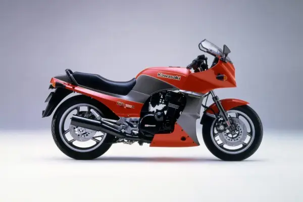 Pomarańczowy motocykl Kawasaki GPZ900R z szarymi akcentami, z lat 80., z owiewką i sportowym wyglądem.