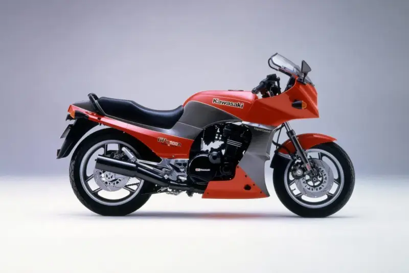 Pomarańczowy motocykl Kawasaki GPZ900R z szarymi akcentami, z lat 80., z owiewką i sportowym wyglądem.