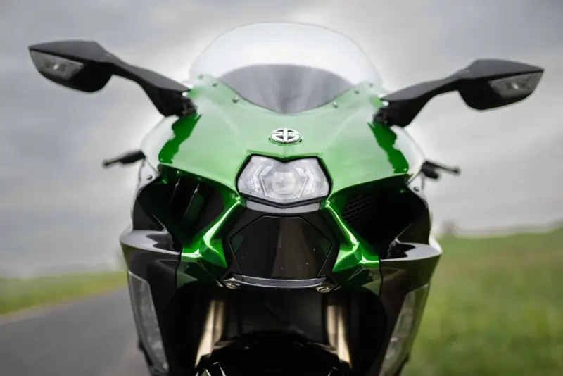 Przód zielono-czarnego motocykla Kawasaki Ninja H2 z błyszczącym logo i ostrymi liniami, gotowy do jazdy.