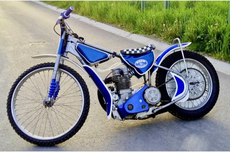 Niebieski motor żużlowy na asfalcie. Zastanawiasz się, ile kosztuje motor żużlowy? Ten wygląda na gotowy do startu!
